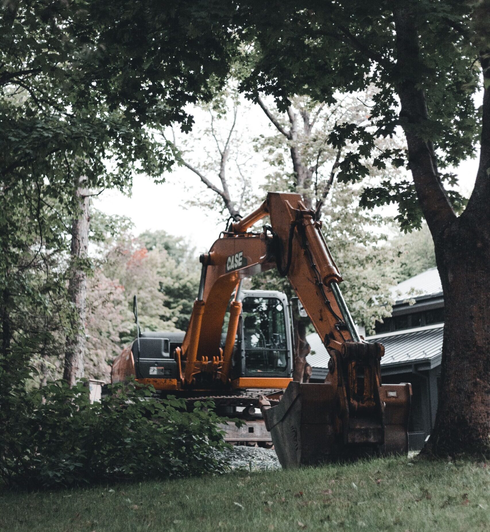Excavator parked beside a mature shade tree at a home construction site that needs tree protection in Chattanooga, TN